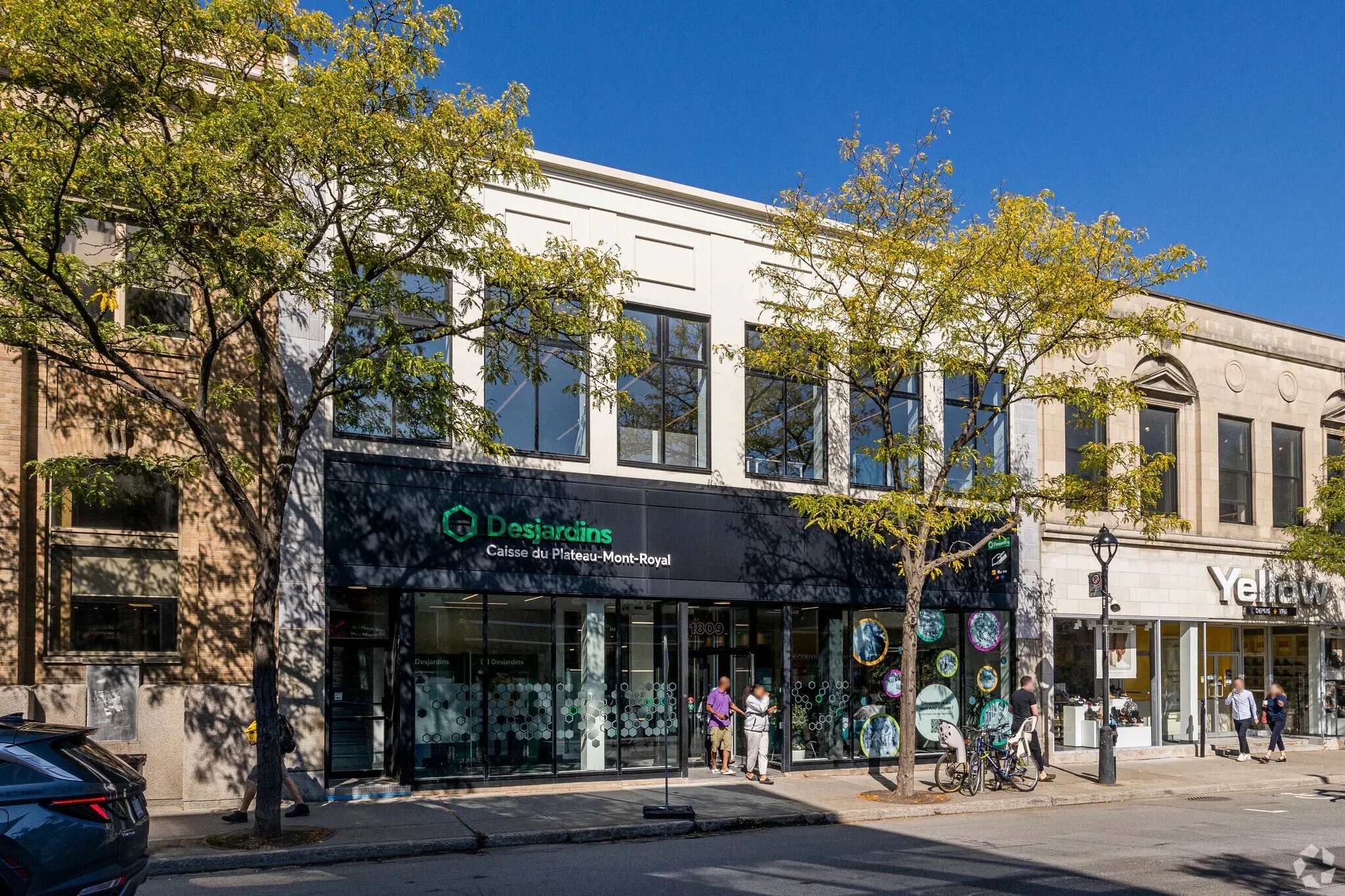 1807-1809 Mont-Royal Est: white stone and glass storefront with a Desjardins branch at street level and offices above
