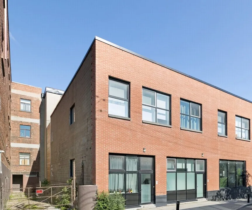 Marie-Anne Lofts: two-storey red brick building with black window frames and ground-floor commercial units, Plateau Mont-Royal