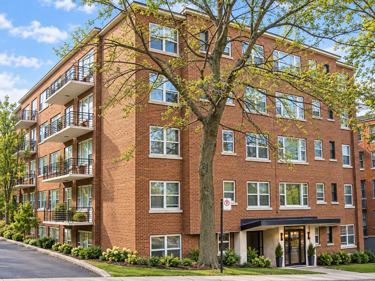 Le Crestview: five-storey red brick apartment building with balconies and a canopied entrance, on a tree-lined street in Côte-des-Neiges